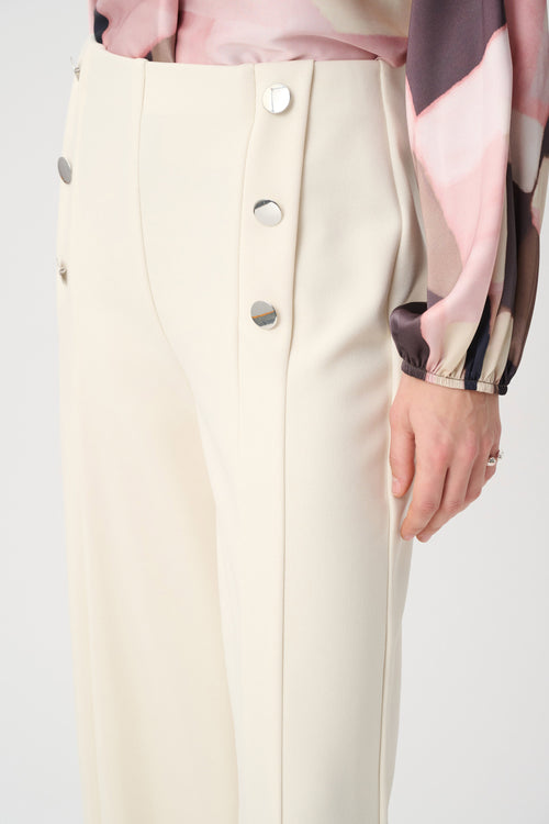 Pantalon large ivoire bouleau Joseph Ribkoff 264087, taille haute, pli marqué et doubles boutons argentés. Coupe fluide et structurée. Parfait bureau ou soirée.