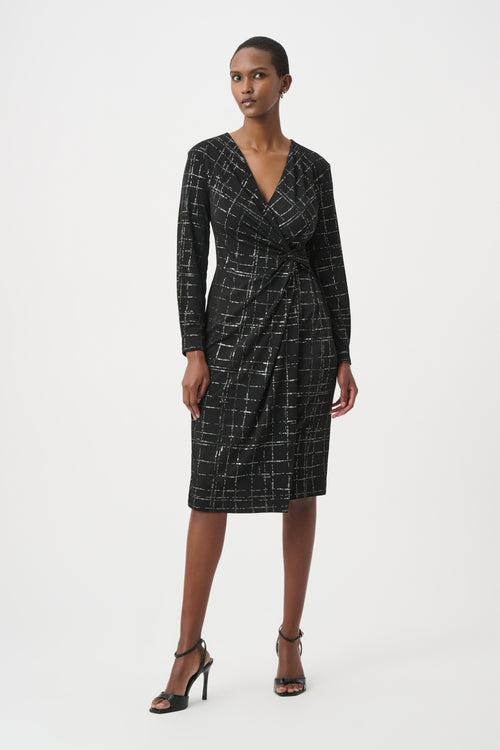 Robe portefeuille Joseph Ribkoff 264186 en jersey noir avec quadrillage métallisé argenté. Col V croisé, nœud taille, manches longues, longueur midi. Parfaite soirée ou bureau.