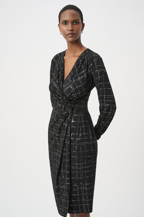 Robe portefeuille Joseph Ribkoff 264186 en jersey noir avec quadrillage métallisé argenté. Col V croisé, nœud taille, manches longues, longueur midi. Parfaite soirée ou bureau.