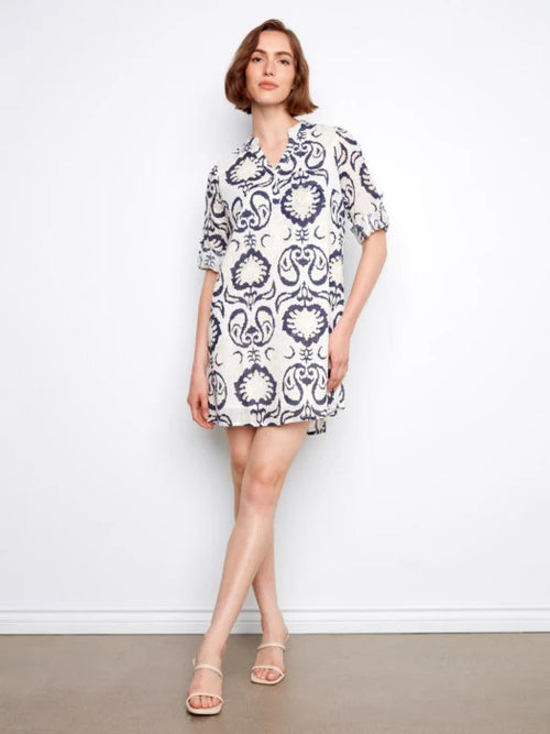 Robe Charlie B c3253 : blanche à motif baroque bleu marine, manches courtes, encolure fendue. Parfaite pour été. Style élégant et frais.