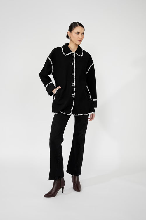 Manteau en laine noire Frank Lyman 251734 avec surpiqûres blanches contrastantes. Élégant, chaud et polyvalent. Parfait pour l'automne et l'hiver québécois.
