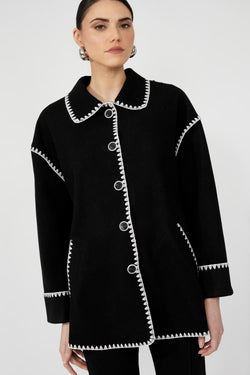 Manteau en laine noire Frank Lyman 251734 avec surpiqûres blanches contrastantes. Élégant, chaud et polyvalent. Parfait pour l'automne et l'hiver québécois.