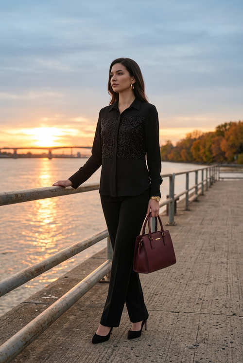 Pantalon chic noir, pose de trois quarts au bord du fleuve au coucher du soleil